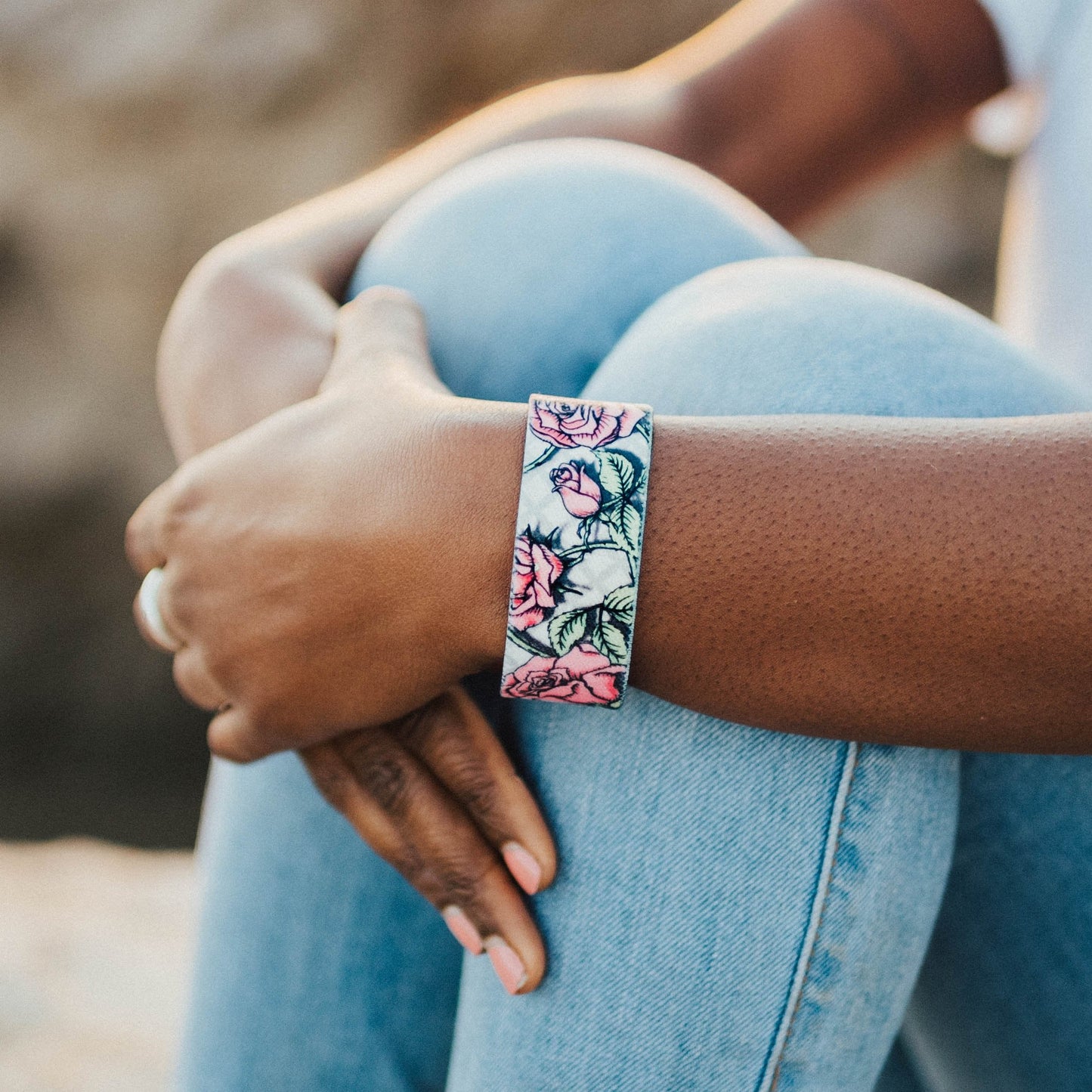 Lifestyle image close up of someone's arms crossed in front of their knees with Thank You on their wrist