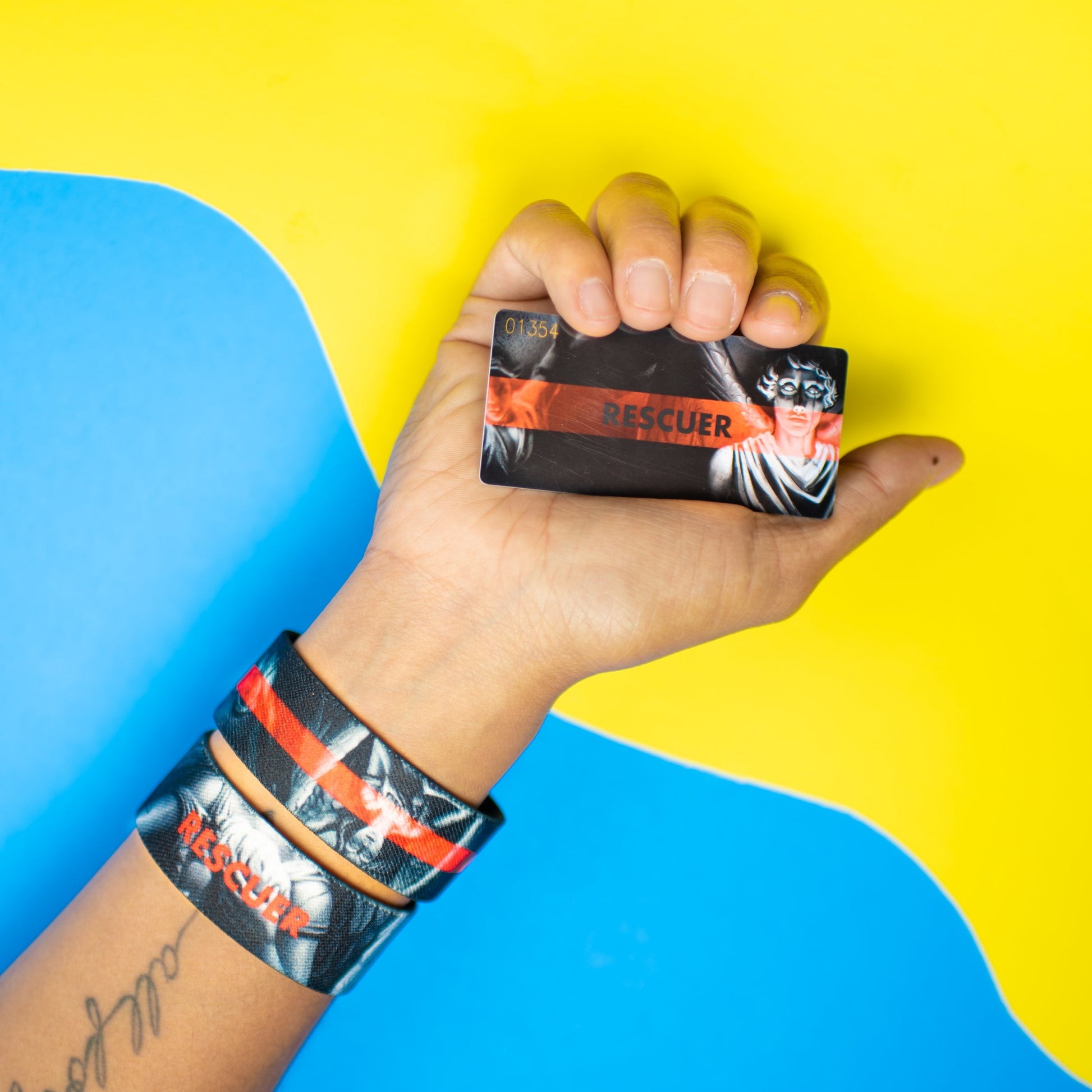 Studio Image of hand holding card that says Rescuer with 2 Rescuer straps on their wrist