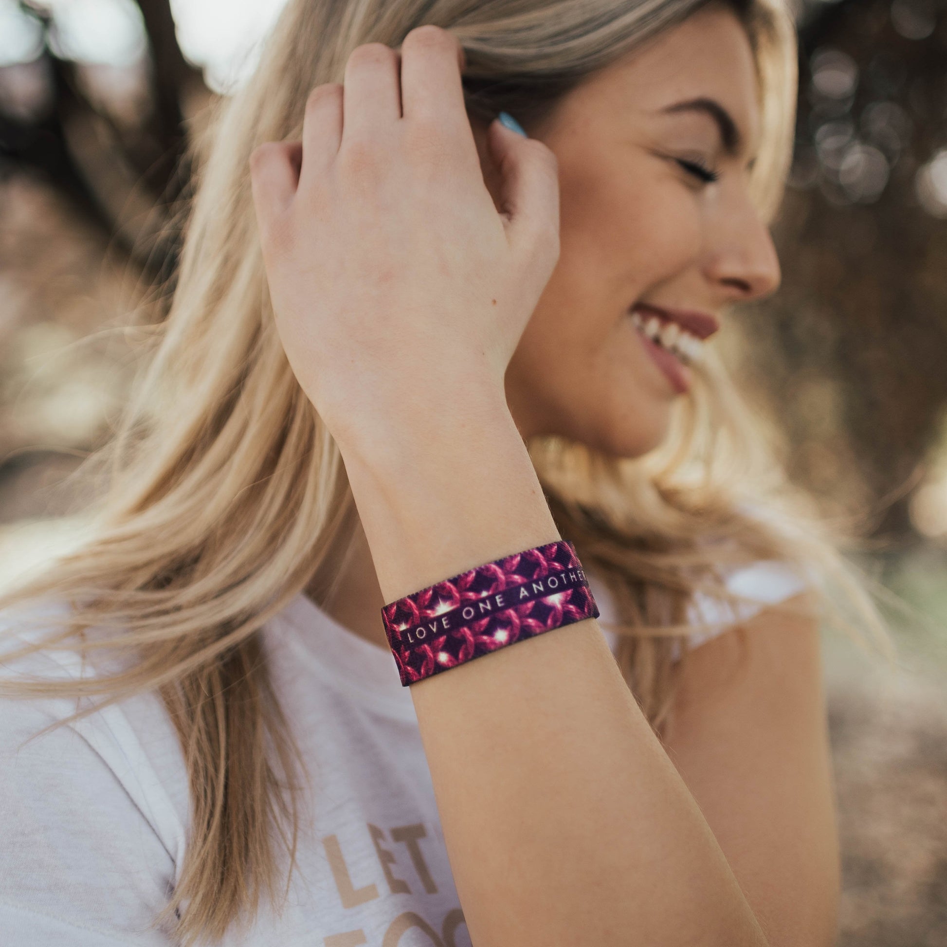 Lifestyle image of Love One Another on wrist of smiling model