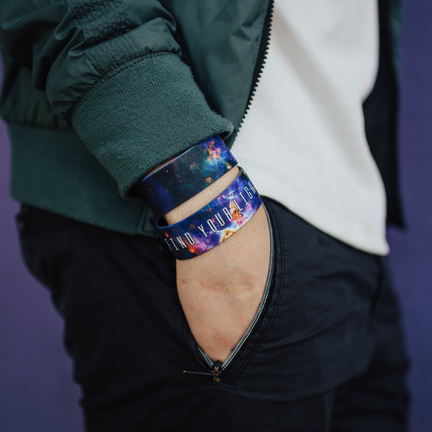 Lifestyle close up image of model's hand in their pocket and wearing two Find Your Light straps 