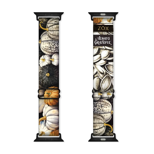 This is a watchband that has pumpkins on the outside in white, grey, black and burnt orange colors. The inside has pumpkin seeds and says Always Grateful. 