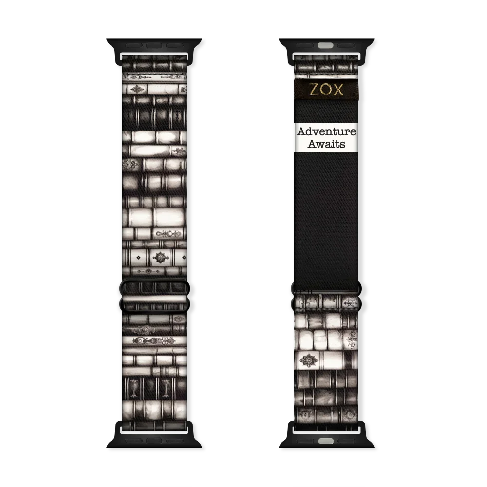 Watchband that is ornate books stacked on top of each other in various shades of black and white. The inside is the same and reads Adventure Awaits. 
