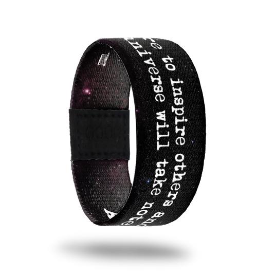 Outside design of Aspire To Inspire has a dark black and bits of purple space background with Aspire to inspire others and the universe will take note in white text and a small image of a  typewriter in black and white