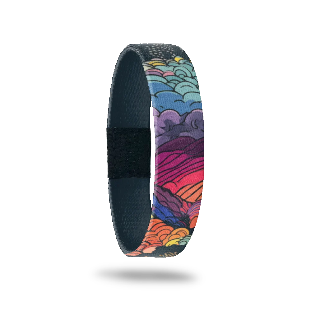 Design is mountains and waves crashing on the shore, all in multicolors with a dark grey sky and stars. Inside is dark gray and reads Beauty In The Storm. 