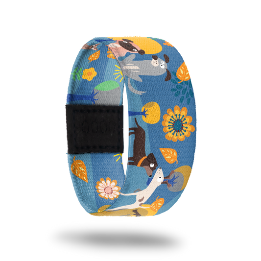 Blue strap with different colored and types of dogs all over with yellow flowers and trees. Inside is the same and reads Best Buds.