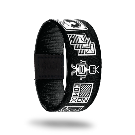 This is a reversible strap. The design is a black base with white pixel images of computer and video games, a little robot, etc. The inside is soldi black and reads Better Nerdy Than Ordinary. 