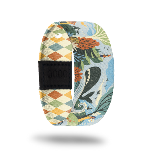 ZOX strap with cartoon design of little boy watching a whale in the ocean on the side of a mountain. Colors are muted orange, beige, blue and green. Comes with a matching pin and collector's box. 