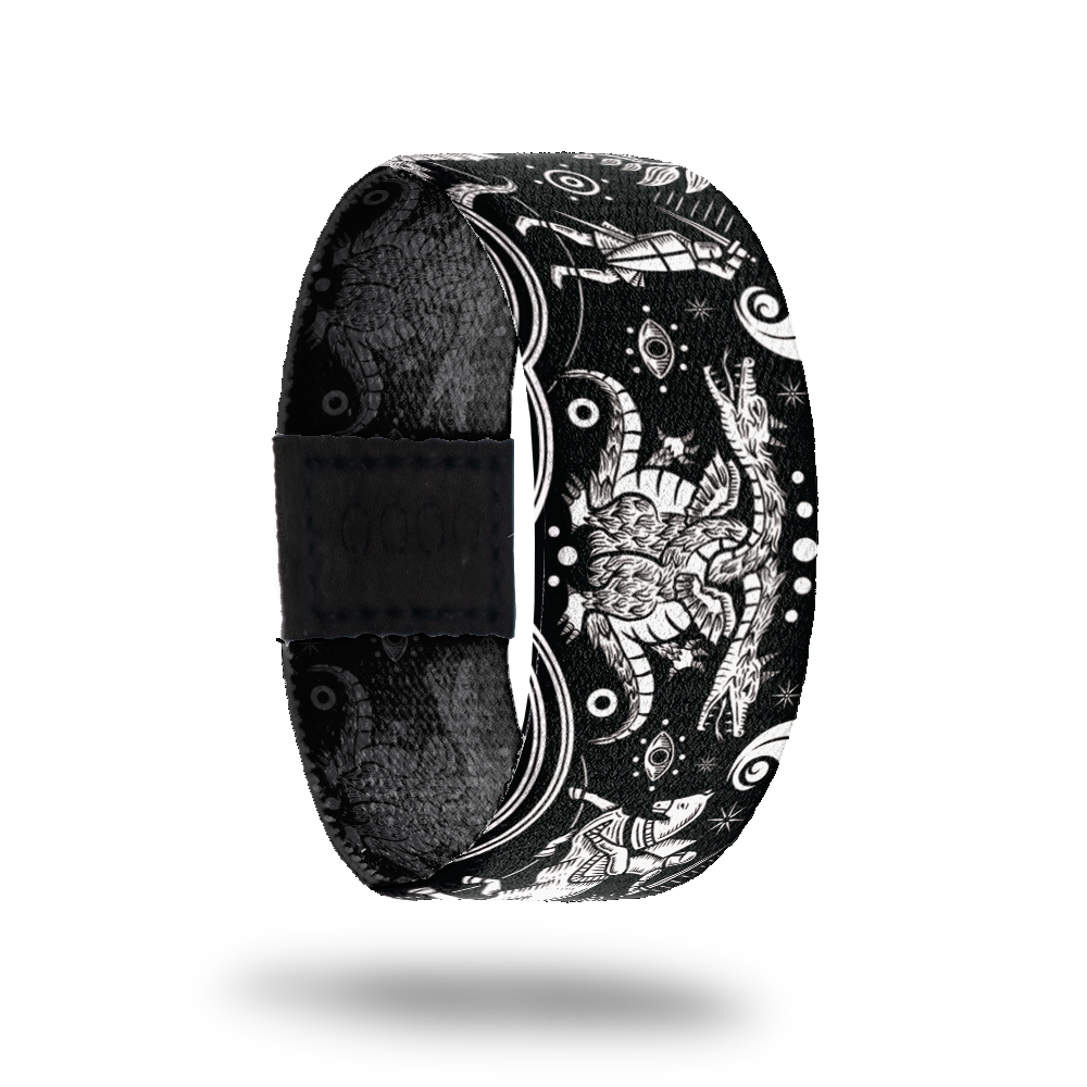 Outside Design of Earn It: black strap with white design of two headed beast being slayed by knights