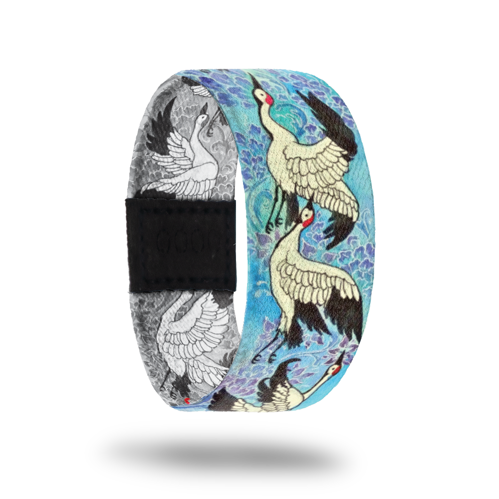 Outside design of Forever Young had a repeating pattern of illustrated cranes in mid flight over a blue background. The illustrated cranes are mostly white with black tipped wings and a little red on the head