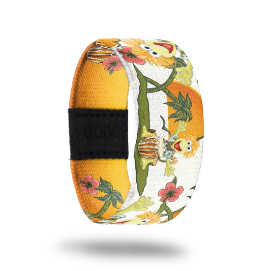 A colorful bracelet featuring Wembley from Fraggle Rock. Wembley is depicted joyfully playing a bongo drum, surrounded by a vibrant design of green vines and red flowers against a background of bright yellow and white. The artwork exudes a cheerful and tropical vibe.