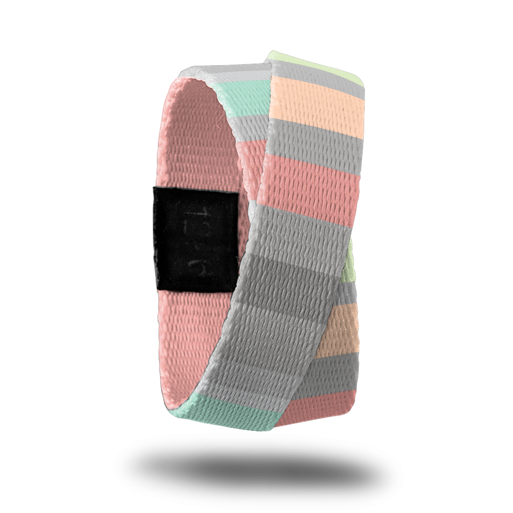 Outside design of How Will You Be Remembered? Subtle knitted look to the design with varying width sizes of rectangles of colors like gray, pink, light orange,and light green. This product, called a double, is thinner and wraps around your wrist twice with the material crossing at one point. 