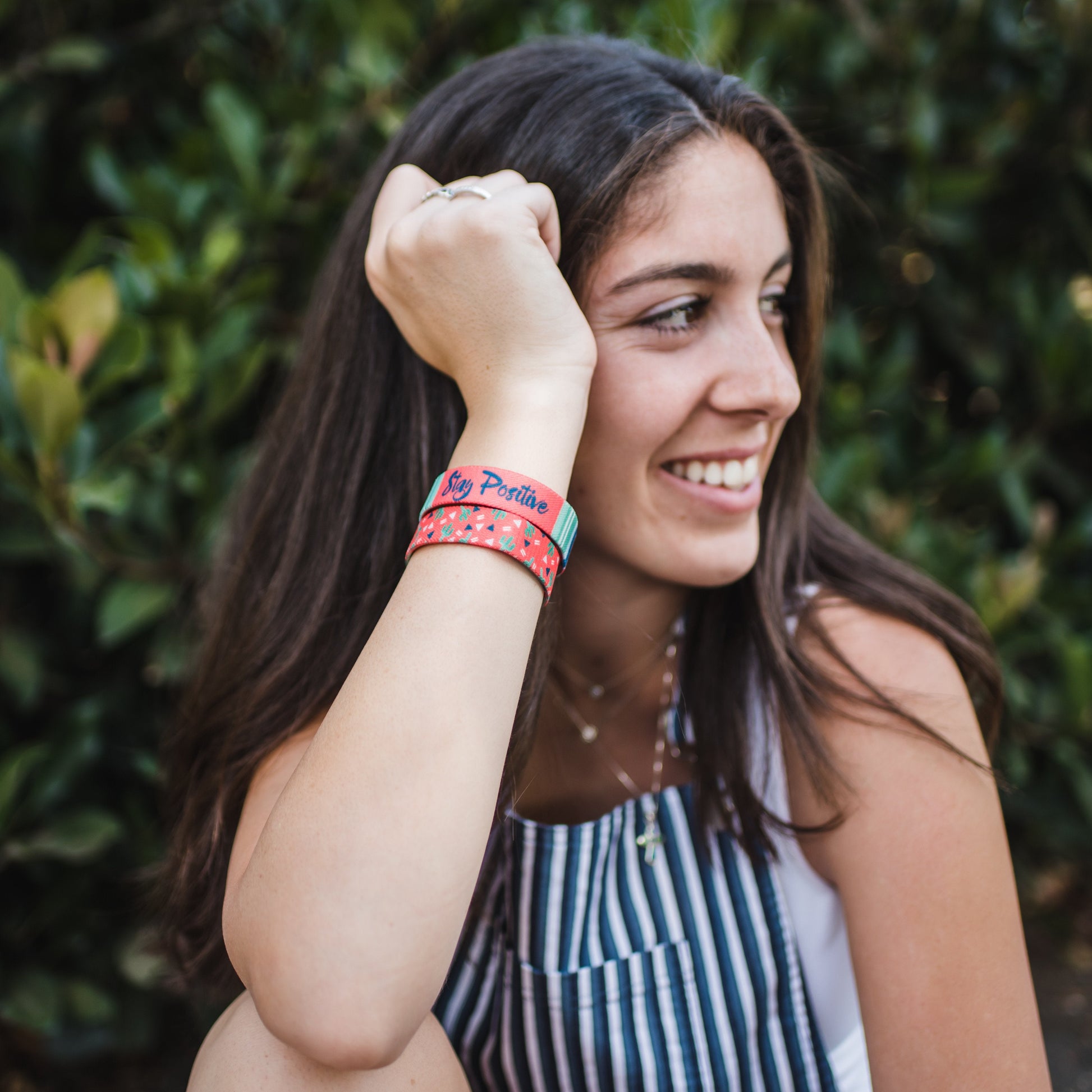Lifestyle image of someone smiling with 2 Stay Positive on their wrist 