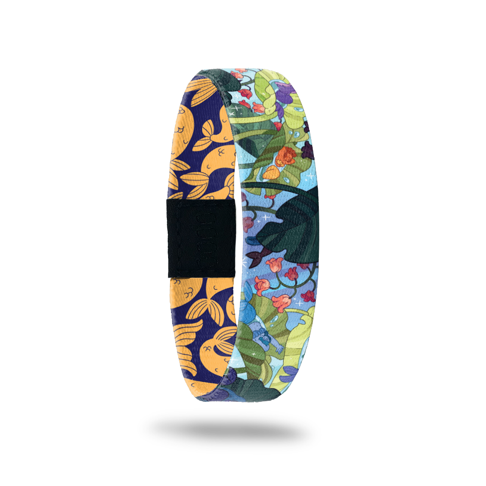 Wristband single is a bluw background with an under the sea image of plant life, fish, etc. The inside is blue and orange mermaid tails and says Make A Splash. This can be purchased with a matching Mermaid charm or separately. 