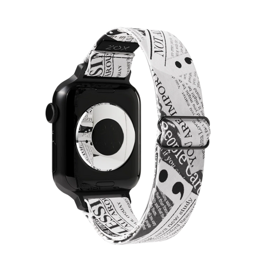 Watchband with a black and white newspaper clipping design. The text is upclose and has random "headlines" of motivational words such as "not alone". The inside is the same and reads My Story Isn't Finished. Check out the size guide for compatible watches.