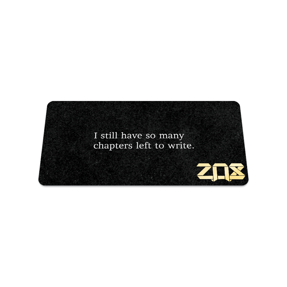 Back of collector's card is solid black. In white text, the quote says "I still have so many chapters left to write."