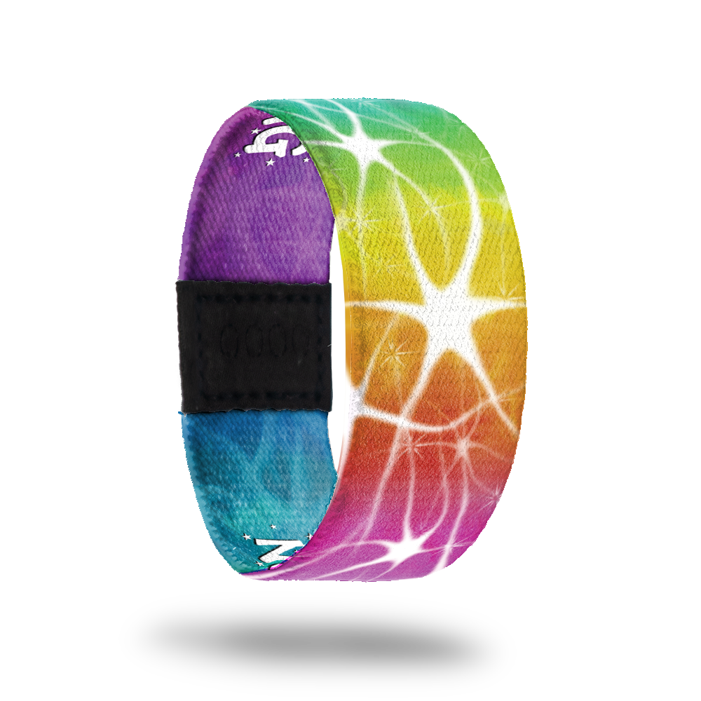 Wristband strap with a very bright and rainbow color-ed outside. All colors blend together and have a white swirl/star design on top. The inside is the same and reads Normal Is Boring. 