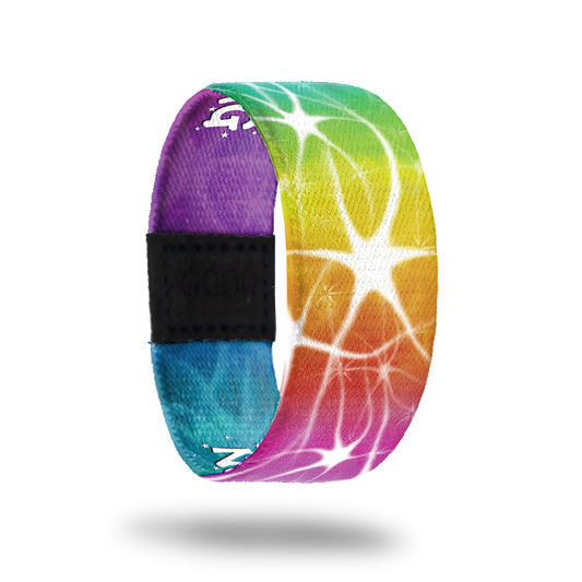 Wristband strap with a very bright and rainbow color-ed outside. All colors blend together and have a white swirl/star design on top. The inside is the same and reads Normal Is Boring. 