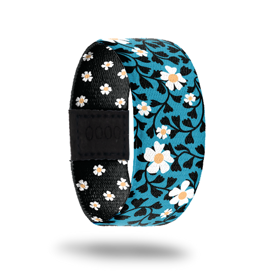 Wristband single that is bright blue with white daisies and black leaves all over. The inside is all black with white daises and reads Open Your Heart. 