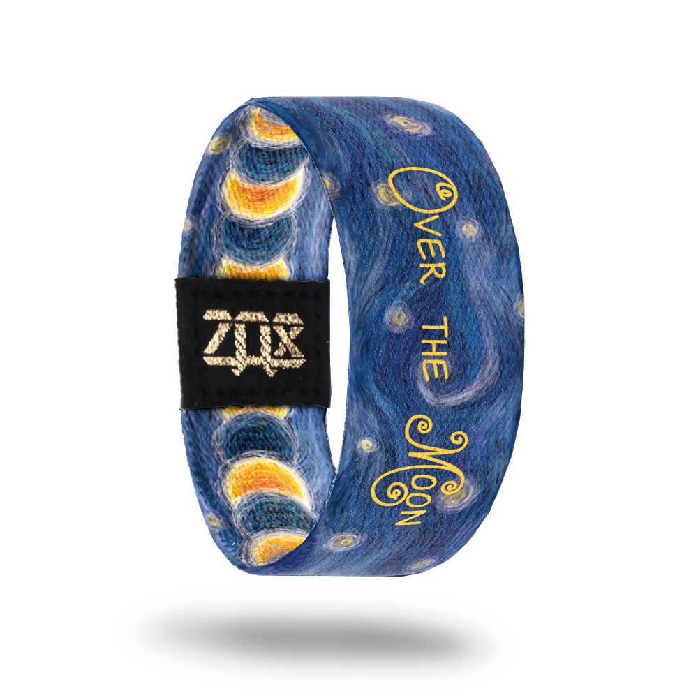 Inside Design of Over the Moon: dark blue design with white, yellow, gold and blue sketches of the night sky with overlaying text ‘Over the Moon’
