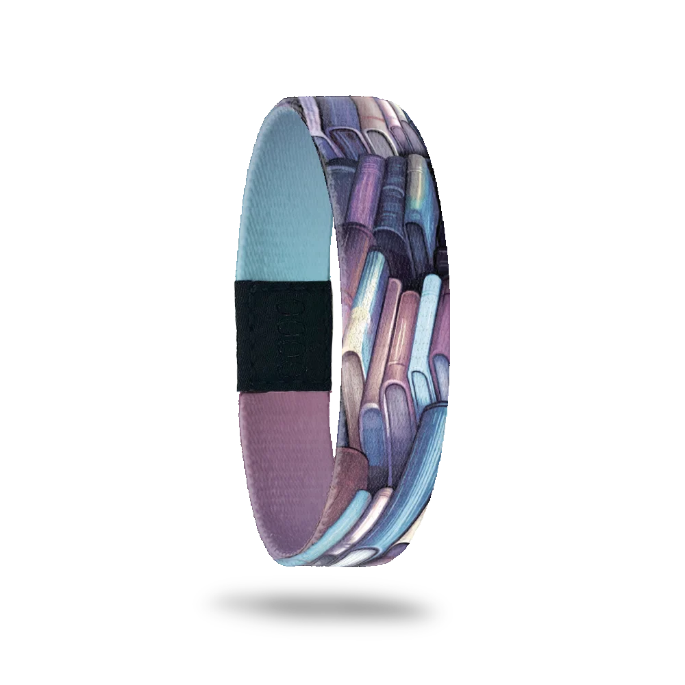 Wristband single with purple and blue books on a shelves all over. The inside is blue and purple gradient and reads Page Turner.