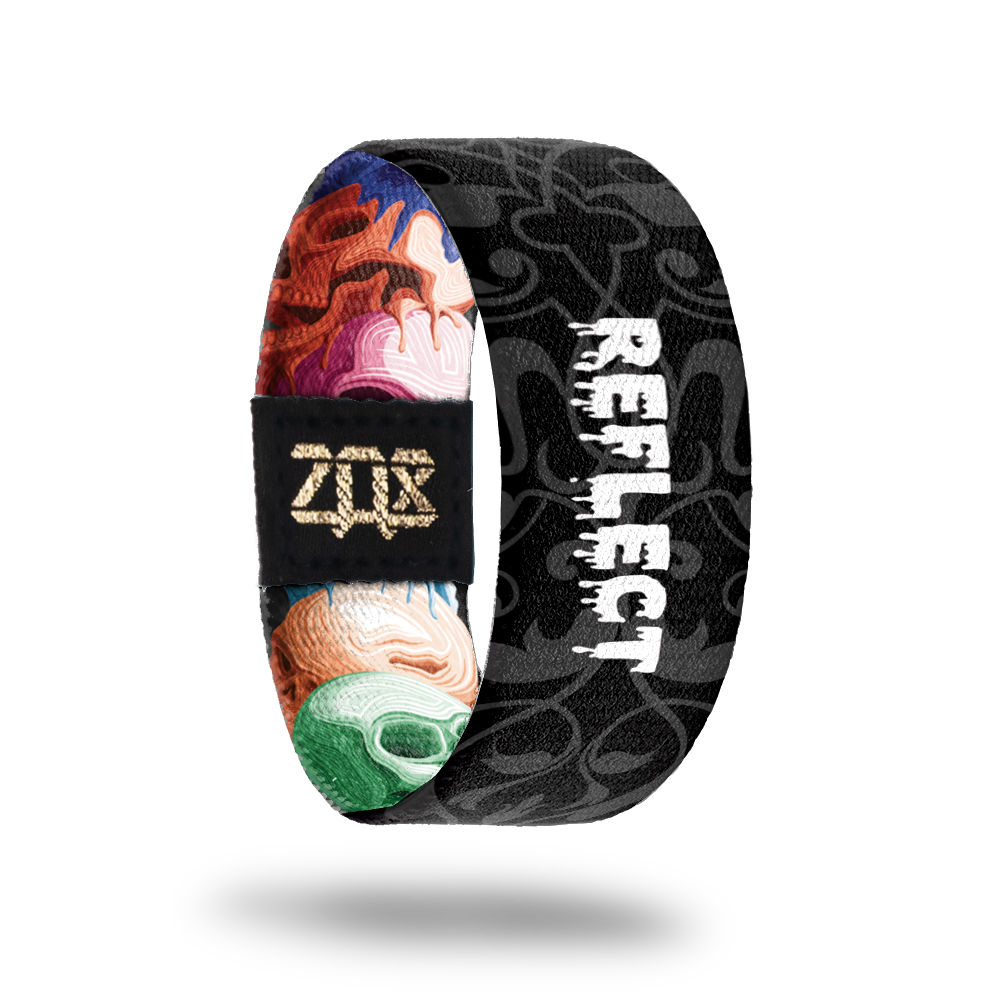 inside of the wristband with the type Reflect on it. Background is a black and white version of the hand drawn skulls