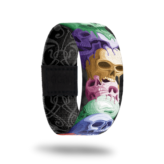 product image of front of wristband named Reflect. The design is a stack of hand drawn skulls in different colors such as purple, gold, pink, blue, and green