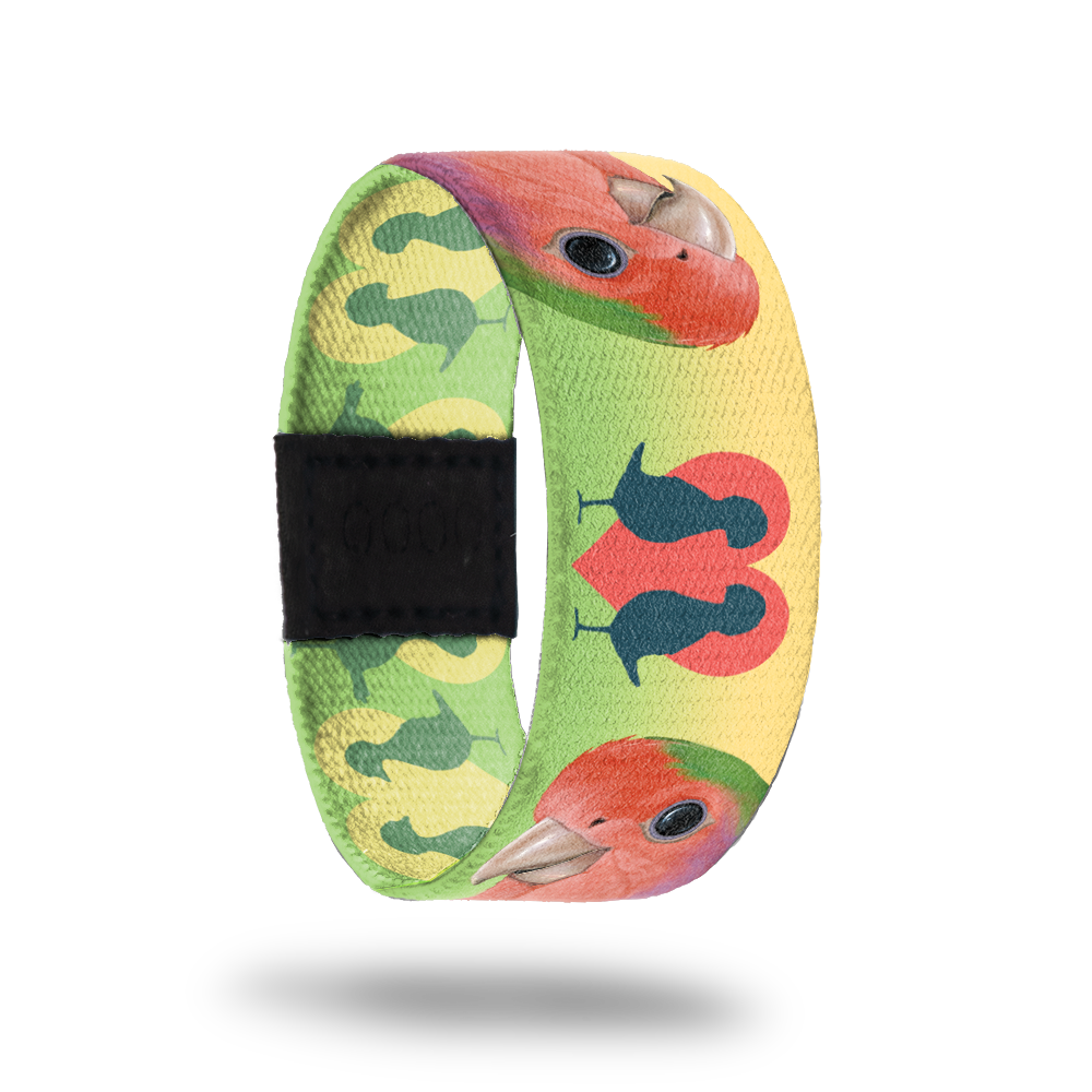 Still image of outside design for the parrot. It has a blended green and yellow background with the parrot being pink with a little bit of green and tan 