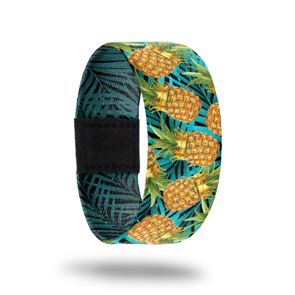 An elastic wristband that has a design on the front of pineapples wearing crowns with A bright blue background