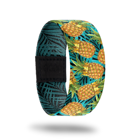 An elastic wristband that has a design on the front of pineapples wearing crowns with A bright blue background