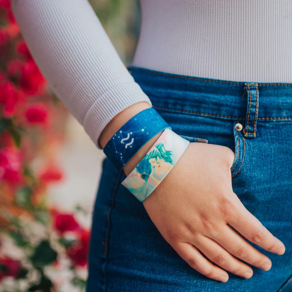 Lifestyle close up image of model's hand in their pocket and wearing two Aquarius straps 
