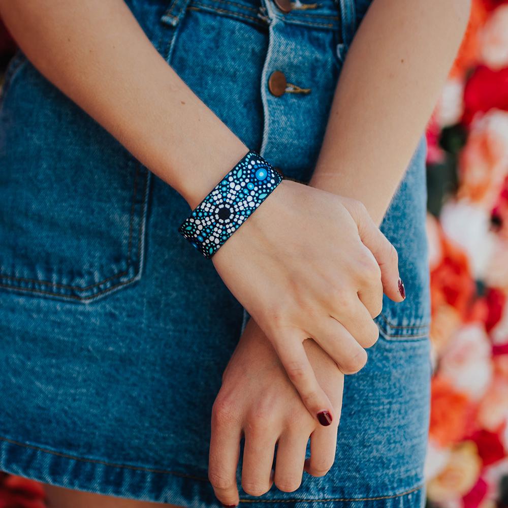 Studio image close up hands crossed one atop the other with Be Kind on 1 wrist