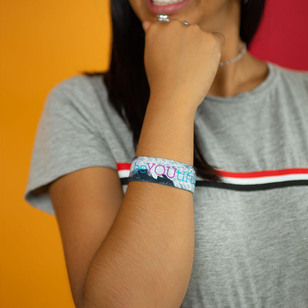 Studio Image close up of BeYOUtiful on woman's wrist while they are in a thinking pose
