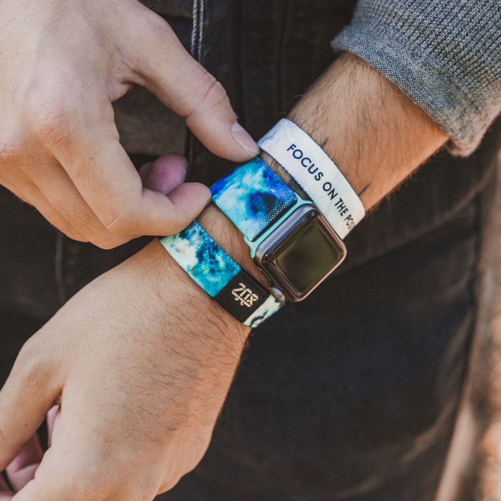 This is a lifestyle photo of someone grabbing the watchband. They are wearing the watchband on an Apple watch. The have the matching wristband on either side of the watch, one showing the outside and one showing the inside. 