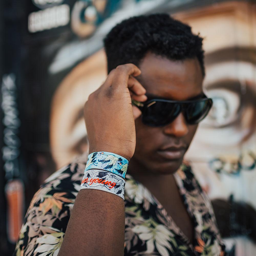 Life Style image of someone adjusting their sunglasses and they have 2 Forever Young straps on their wrist
