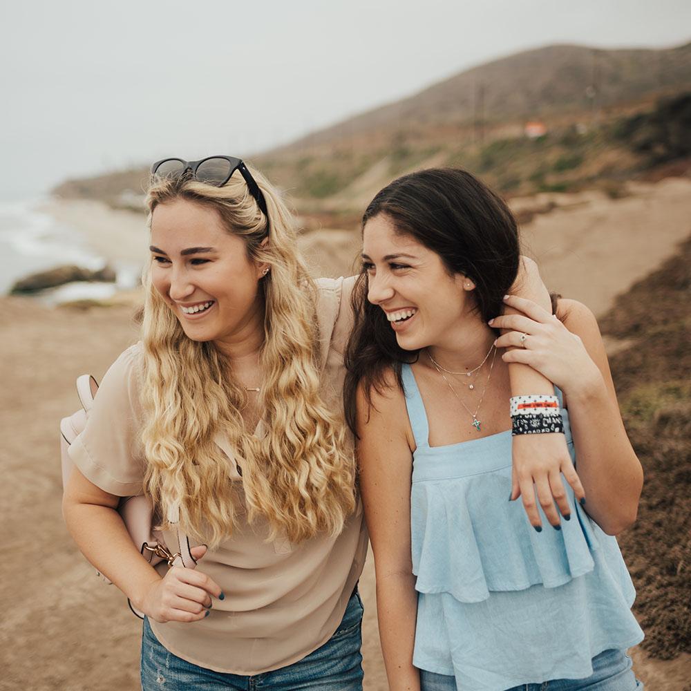 Lifestyle image of woman putting arm around the shoulders of another woman while having 2 Good Vibes Only straps on one wrist