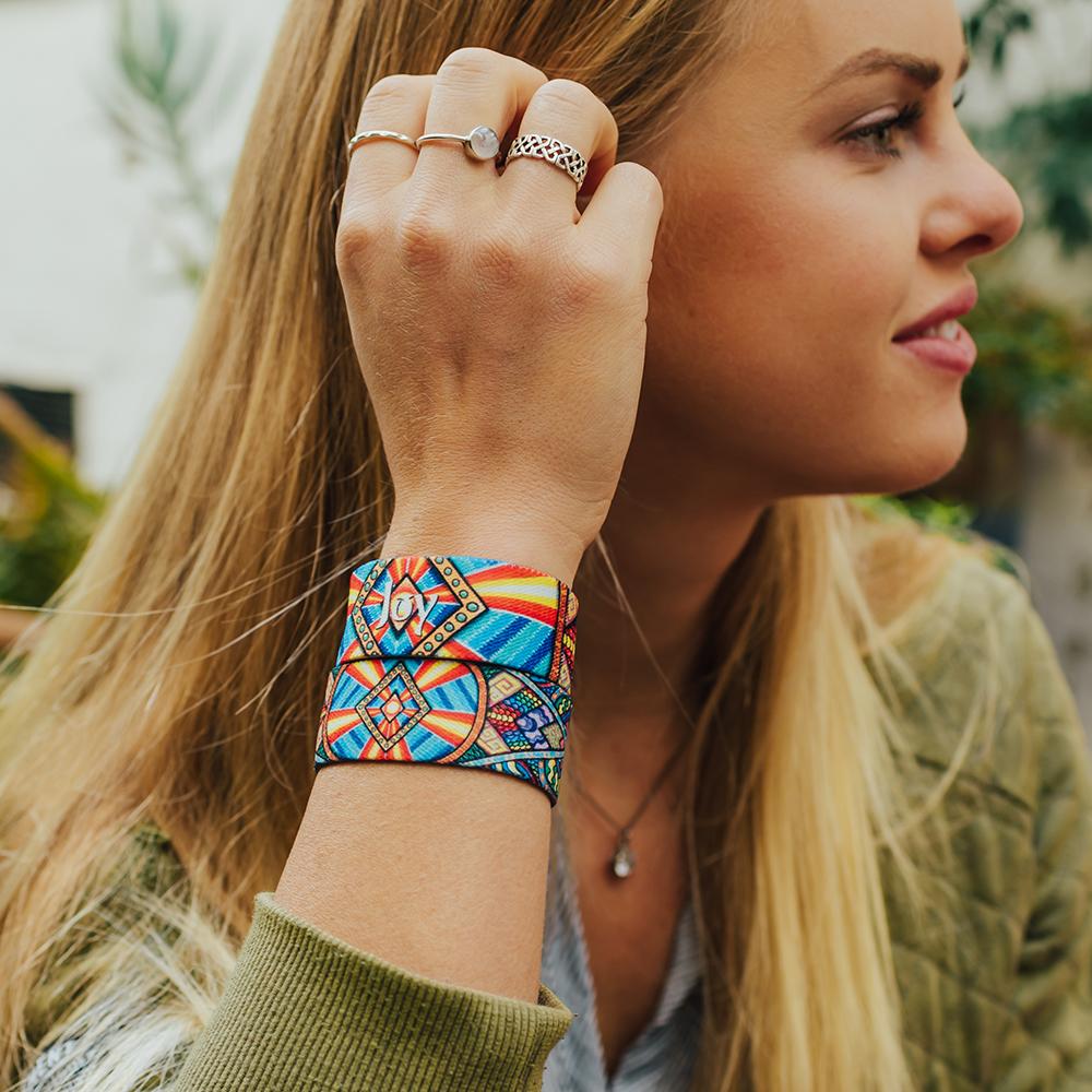 Lifestyle side portrait image of someone fixing their hair and wearing two Joy straps on one arm