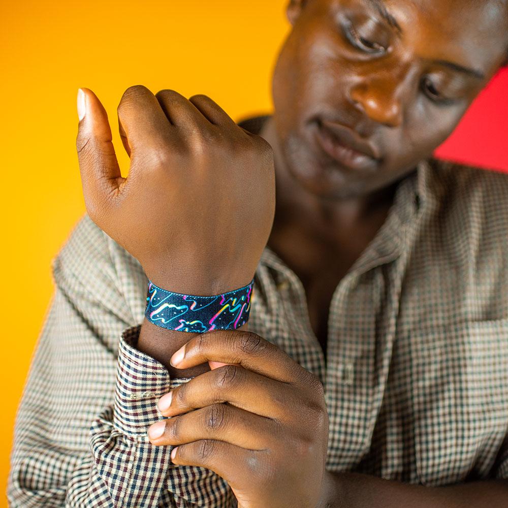 Studio close up of Let Go on model's wrist as they adjust their shirt sleeve