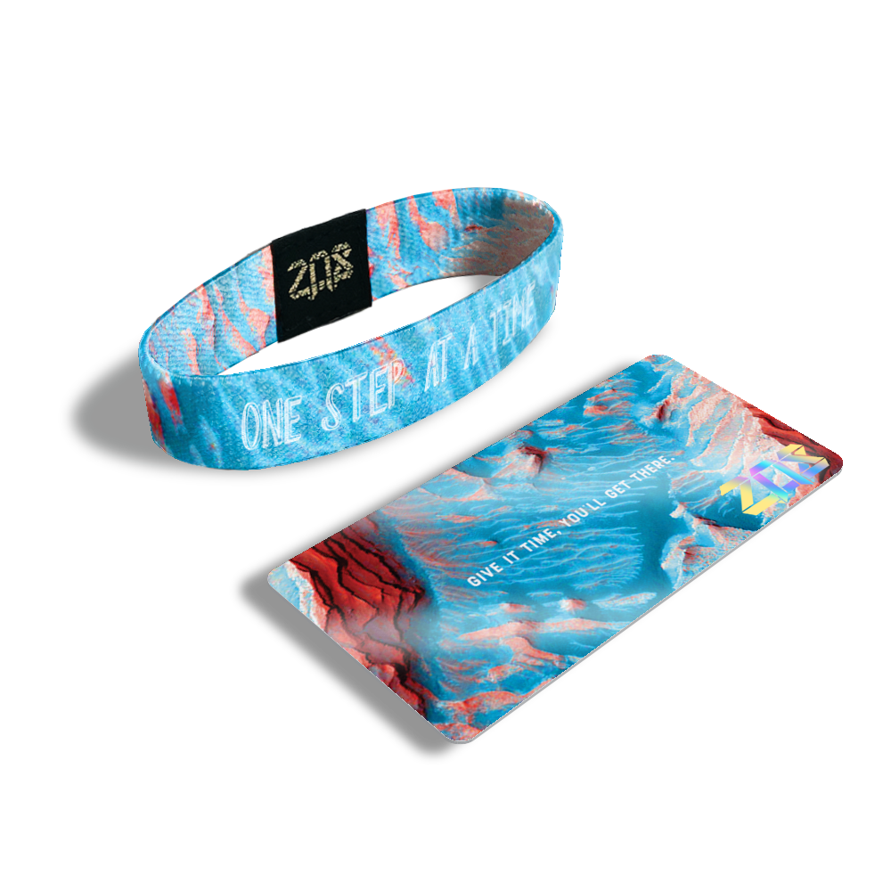 Product photo of the inside of one step at a time. It is an aerial of photoshopped image of Mars that light blue with white text one step at a time overlaying with its card saying 'Give it time, you'll get there.'