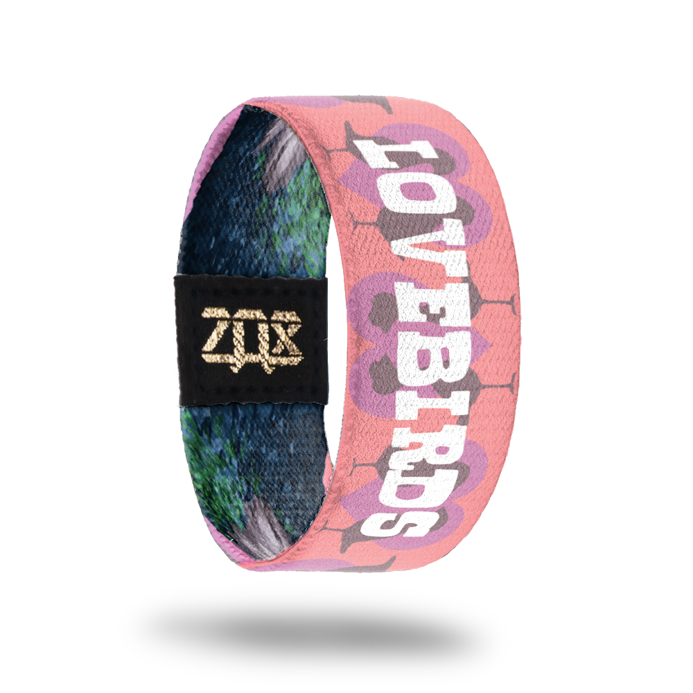 Still image of inside design for pigeon. Light pink background with light purple hearts and the full bird body silhouettes in a dark pink for the background. Lovebirds in the center in large bold text