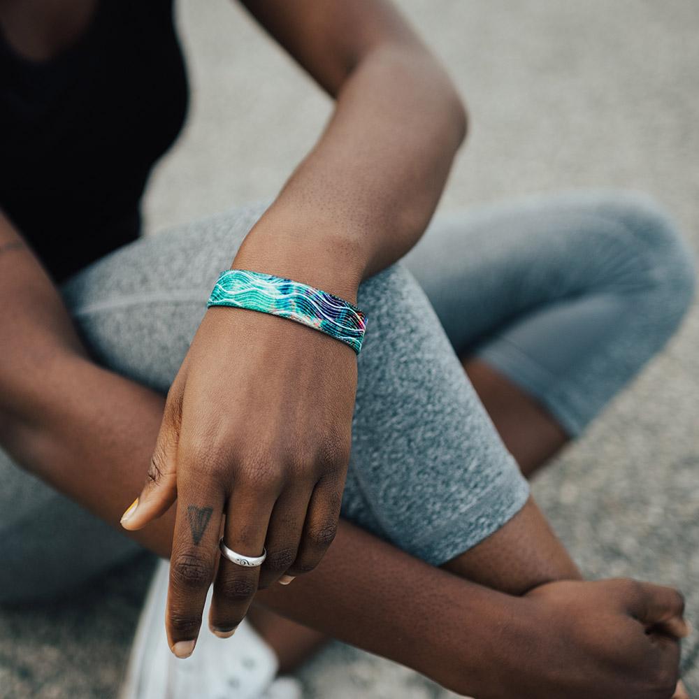 Lifestyle photo of a girl resting her wrist on her knee showing the outside design of the rise above it single
