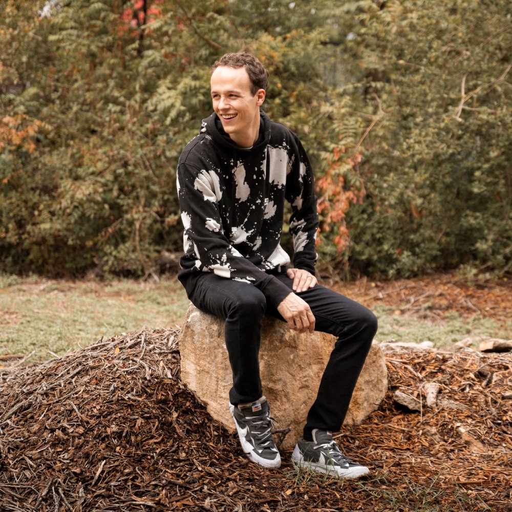 Jordan sitting on a rock, wearing the hoodie. 