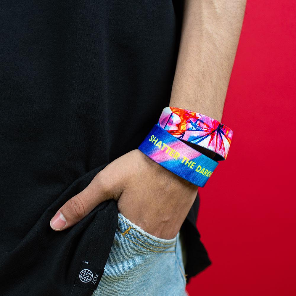 Studio image close up of model's hand in pocket with 2 Shatter The Darkness on wrist