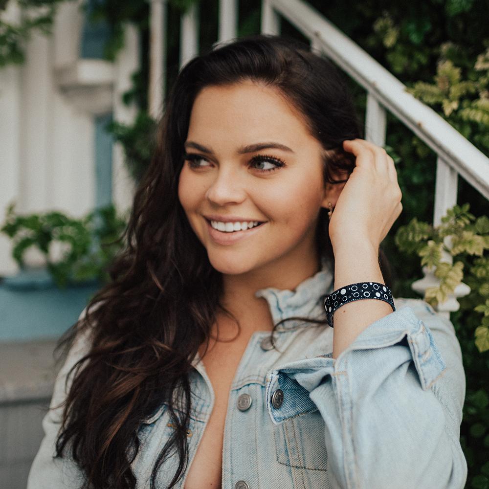 Lifestyle image close up of someone smiling with Take A Chance on their wrist 